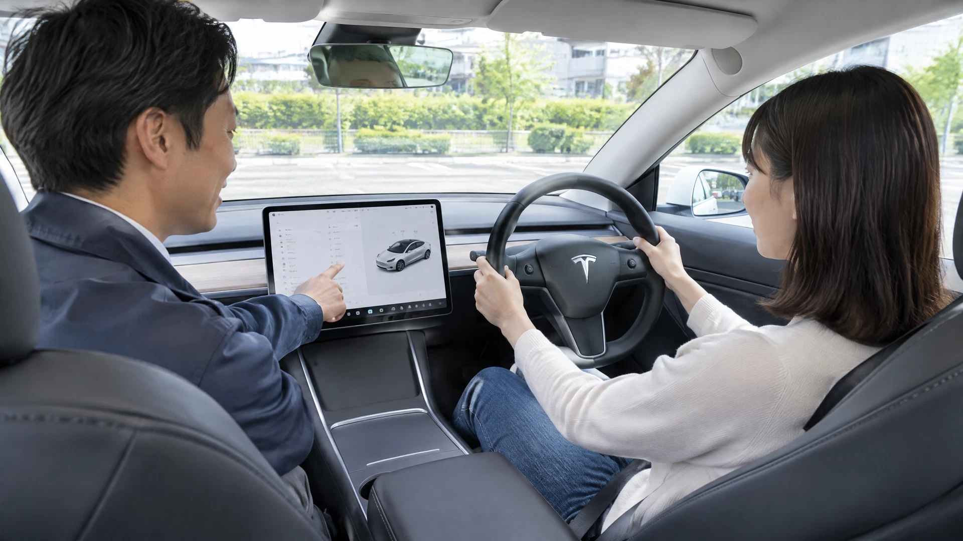 助手席のインストラクターが受講者へテスラ Model 3の操作を説明する様子