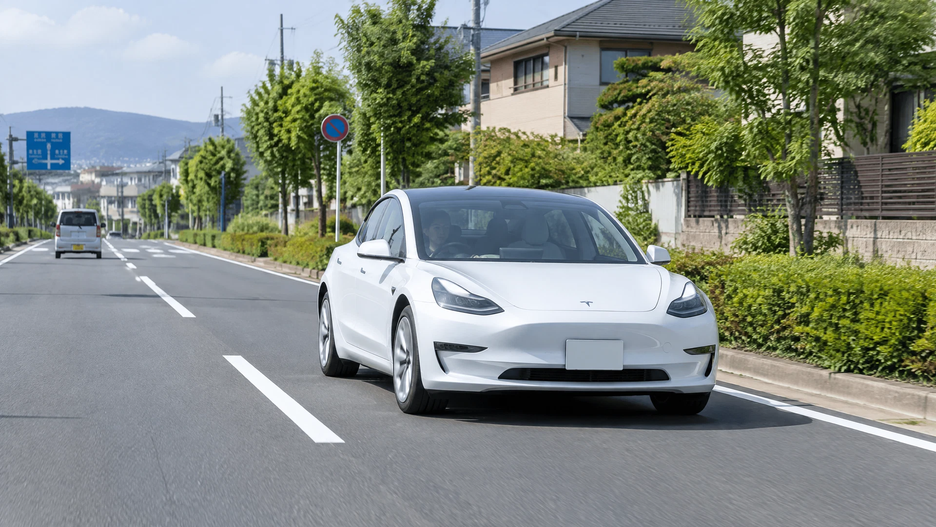 日本の一般道路を安全に走行する白いテスラ Model 3教習車
